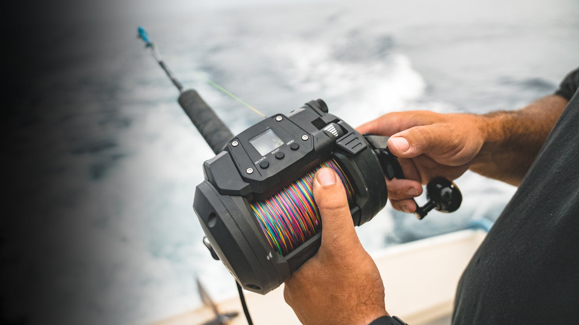 Angler holding a Daiwa Tanacom 1200 loaded with multicolor braid on a boat